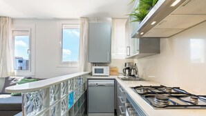 A modern kitchen with a dishwasher, microwave, stove, and a window with curtains. - Bright duplex, consisting of two joined flats (two bedroom + studio) that fit 5 people (Barcelona)
