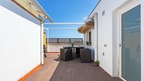 A rooftop terrace with a table and chairs, a potted plant, and a sliding glass door. - Bright duplex, consisting of two joined flats (two bedroom + studio) that fit 5 people (Barcelona)