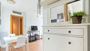 A modern room with a white desk, chairs, a television, a dresser, and a mirror. - Bright duplex, consisting of two joined flats (two bedroom + studio) that fit 5 people (Barcelona)