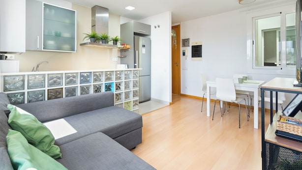 A modern kitchen with a refrigerator, sink, and potted plants. There is a dining area with a table and chairs. - Bright duplex, consisting of two joined flats (two bedroom + studio) that fit 5 people (Barcelona)