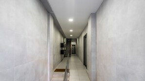 Um corredor moderno e bem iluminado, com uma escada que leva a um andar superior.