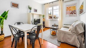 Uma sala de estar moderna com área de jantar, sofá e televisão.