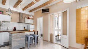 A modern kitchen with a wooden ceiling, white cabinets, and a bar area with stools. - Wake in a luminous, chic and ideally located flat, surrounded by the magic of Barcelona (Barcelona)