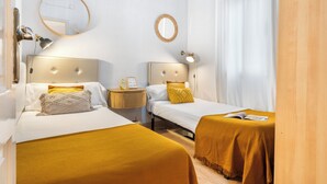 Ein Hotelzimmer mit zwei Betten, einem Nachttisch mit Lampe, einem Spiegel und einem Fenster mit Vorhängen.