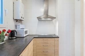 Une cuisine moderne équipée d’une hotte en acier inoxydable, d’un four à micro-ondes et d’une bouilloire posés sur le plan de travail.