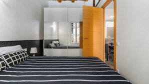 A bedroom with a bed, a wardrobe, a desk, and a chair.