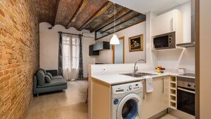 A compact kitchen with a washing machine, a microwave, and a built-in oven.