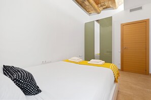 Una camera da letto con un letto, una porta in legno, uno specchio e una coperta gialla.
