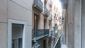 A narrow urban alleyway with buildings on either side, featuring balconies with metal railings and a small street lamp. - Unpack your bags, take a deep salty breath, inhale the sea in, and wonder at the magic of Barcelona (Barcelona)