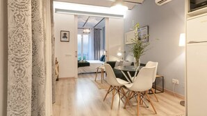 Un salon moderne avec un coin repas, comprenant un canapé, une table à manger avec des chaises et un luminaire suspendu.
