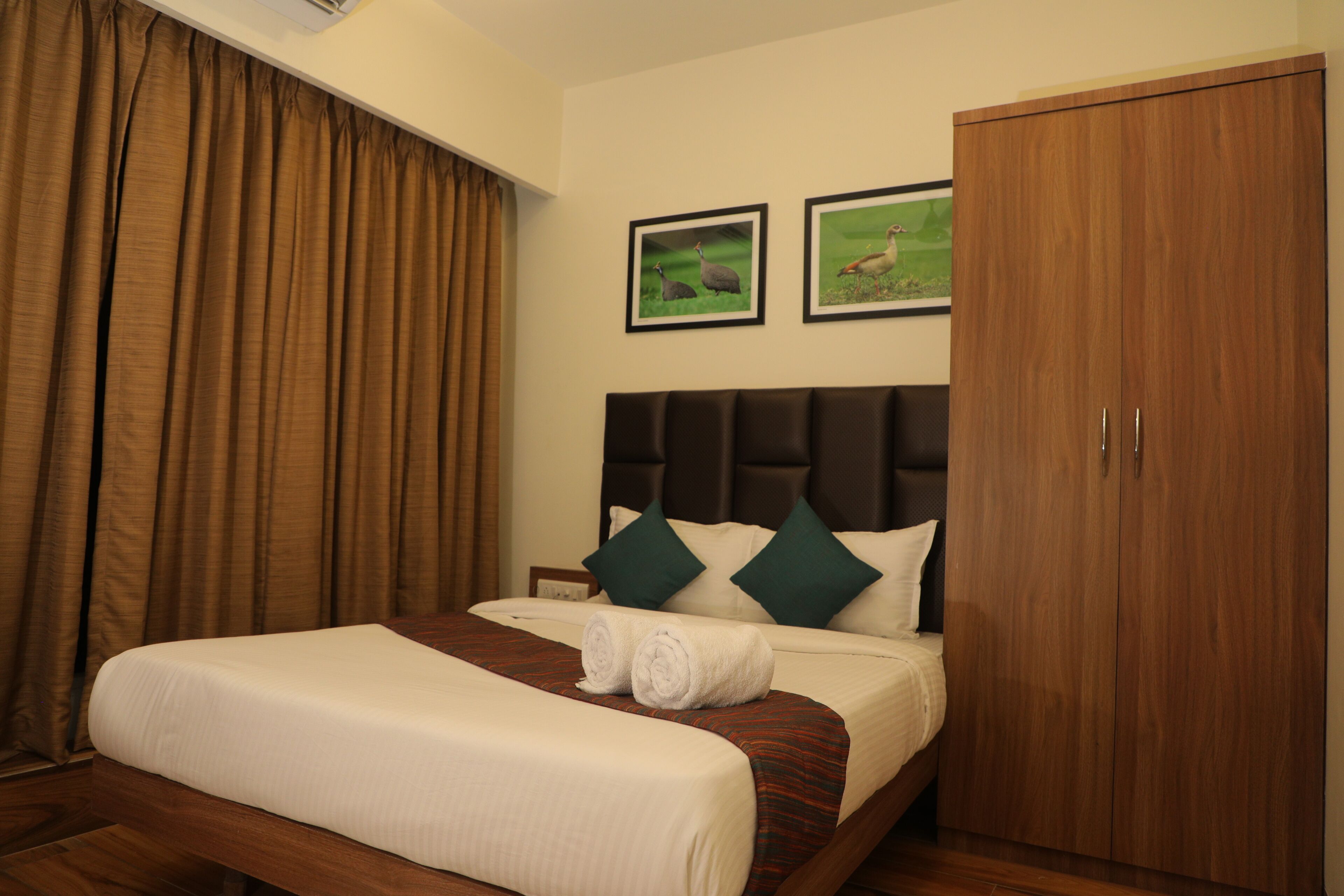 Una habitación de hotel con una cama, un armario y dos cuadros en la pared.