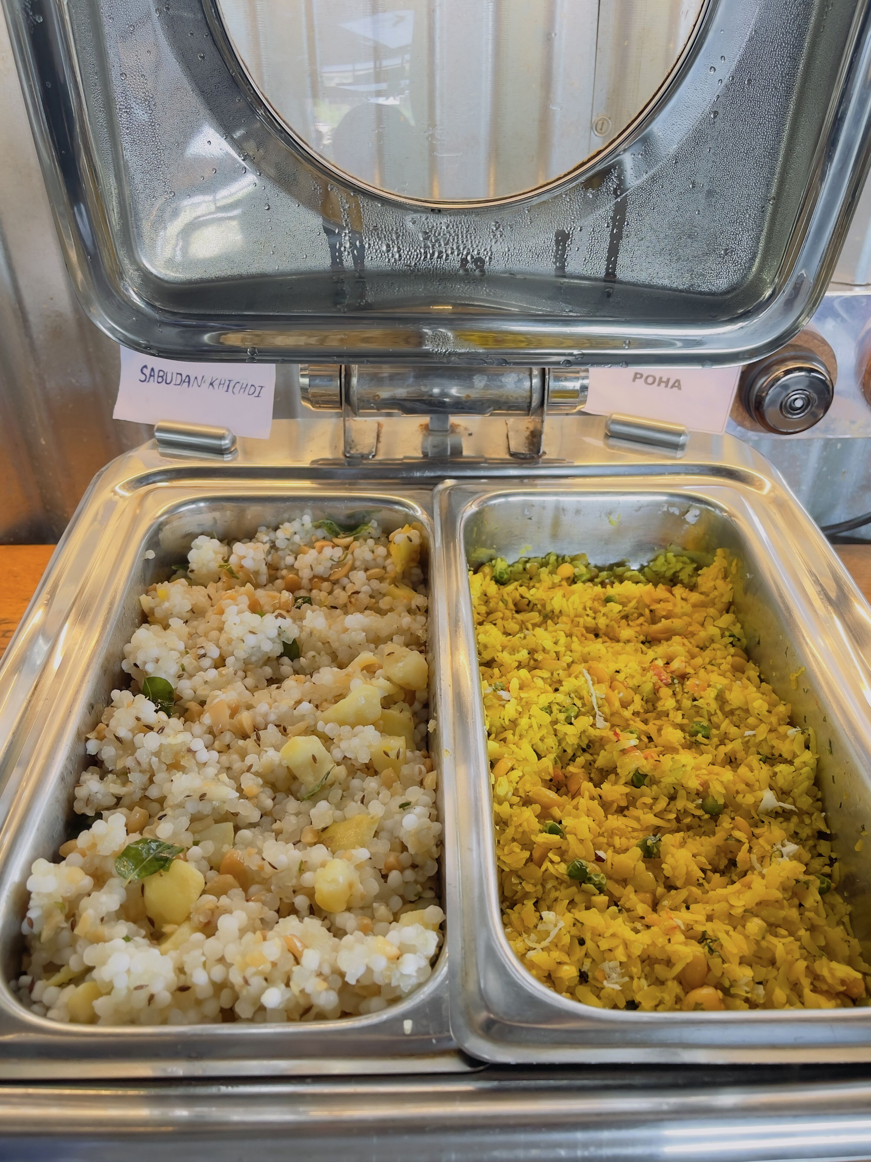 A buffet with two labeled sections, one for sabudan khichdi and one for poha.