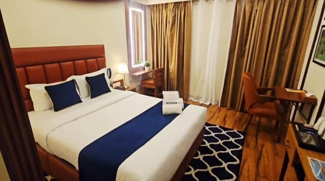 Een hotelkamer met een groot bed, een bureau, een stoel en een raam met gordijnen.