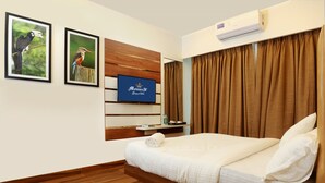 A hotel room with a bed, wooden flooring, a mounted TV, and a window with curtains. - Sky suites by Monarch (Navi Mumbai)