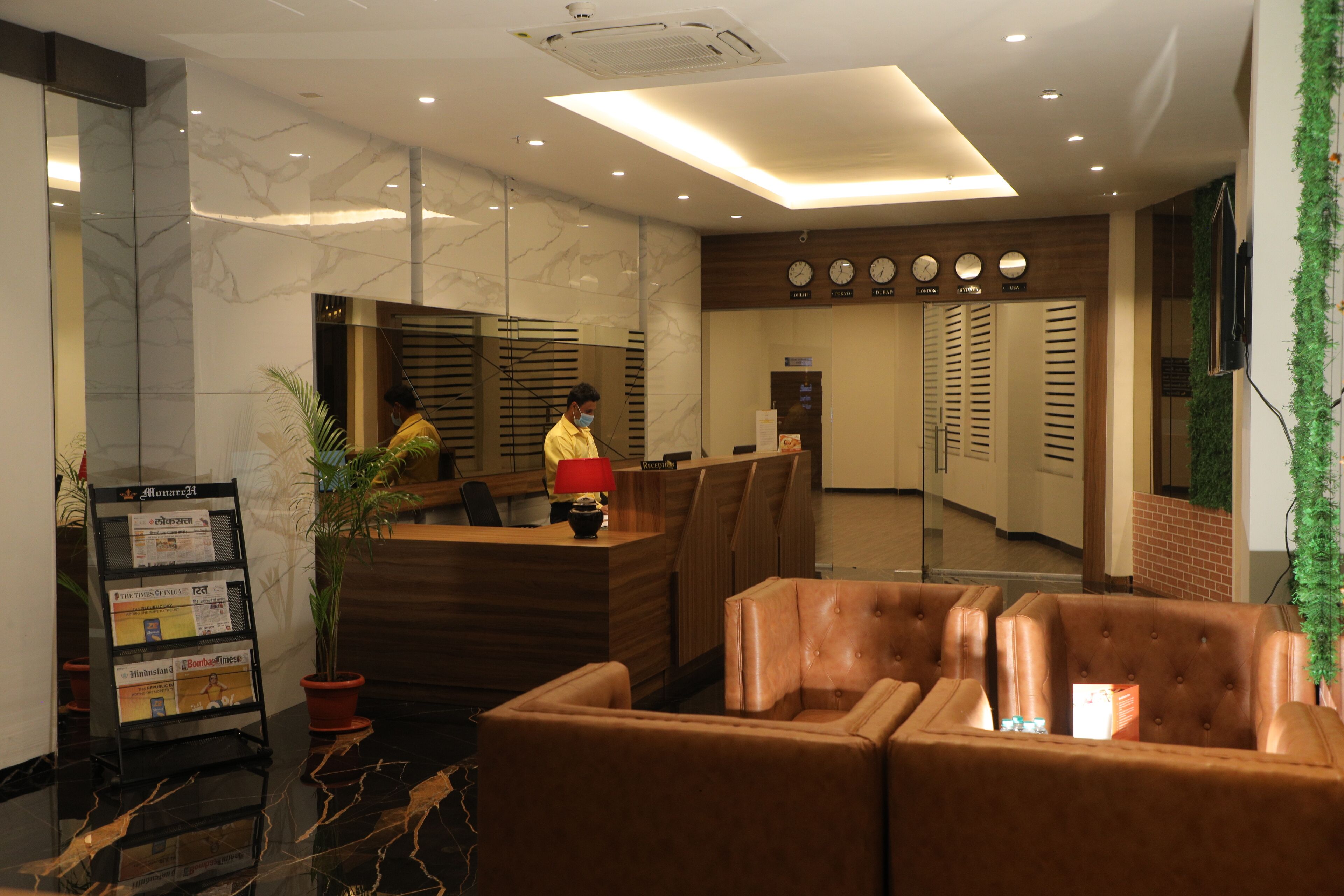 A hotel reception area with a modern design, featuring a reception desk, seating area, and a clock on the wall.