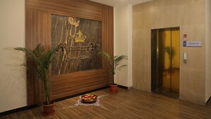 A reception area with a wooden panel wall, a reception desk, potted plants, and a private lift sign. - Sky suites by Monarch (Navi Mumbai)