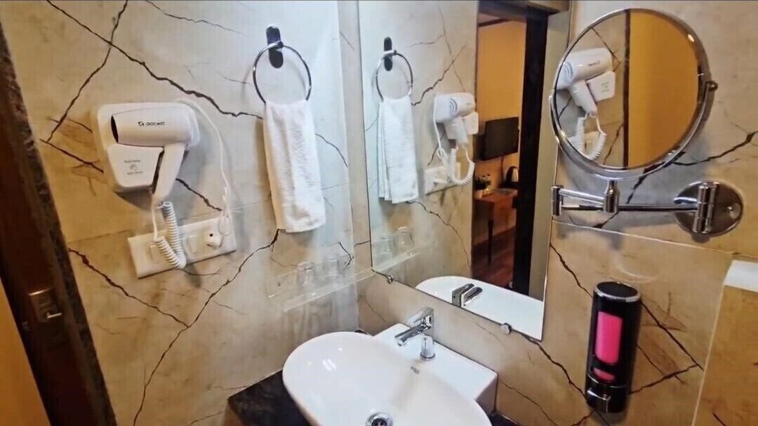 A bathroom with a sink, two hair dryers, a mirror, and a hairbrush.
