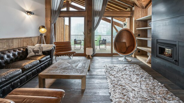 A cozy living room with a leather sofa, a wooden coffee table, a fluffy rug, a hanging light fixture, and a fireplace. - Modern duplex for 10 people near slopes in Courchevel Le Praz (Courchevel)