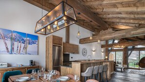 A modern kitchen with wooden beams, a stainless steel refrigerator, and a bar area with bar stools. - Modern duplex for 10 people near slopes in Courchevel Le Praz (Courchevel)