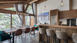 A modern kitchen with wooden cabinets, a stainless steel refrigerator, and a bar area with stools. - Modern duplex for 10 people near slopes in Courchevel Le Praz (Courchevel)