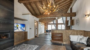 A spacious living area with a fireplace, a wooden ceiling, and a chandelier. - Modern duplex for 10 people near slopes in Courchevel Le Praz (Courchevel)