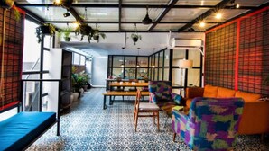 A modern interior with a patterned floor, a sofa, a chair, and hanging plants. - Shubham Vilas - Hostel (New Delhi)
