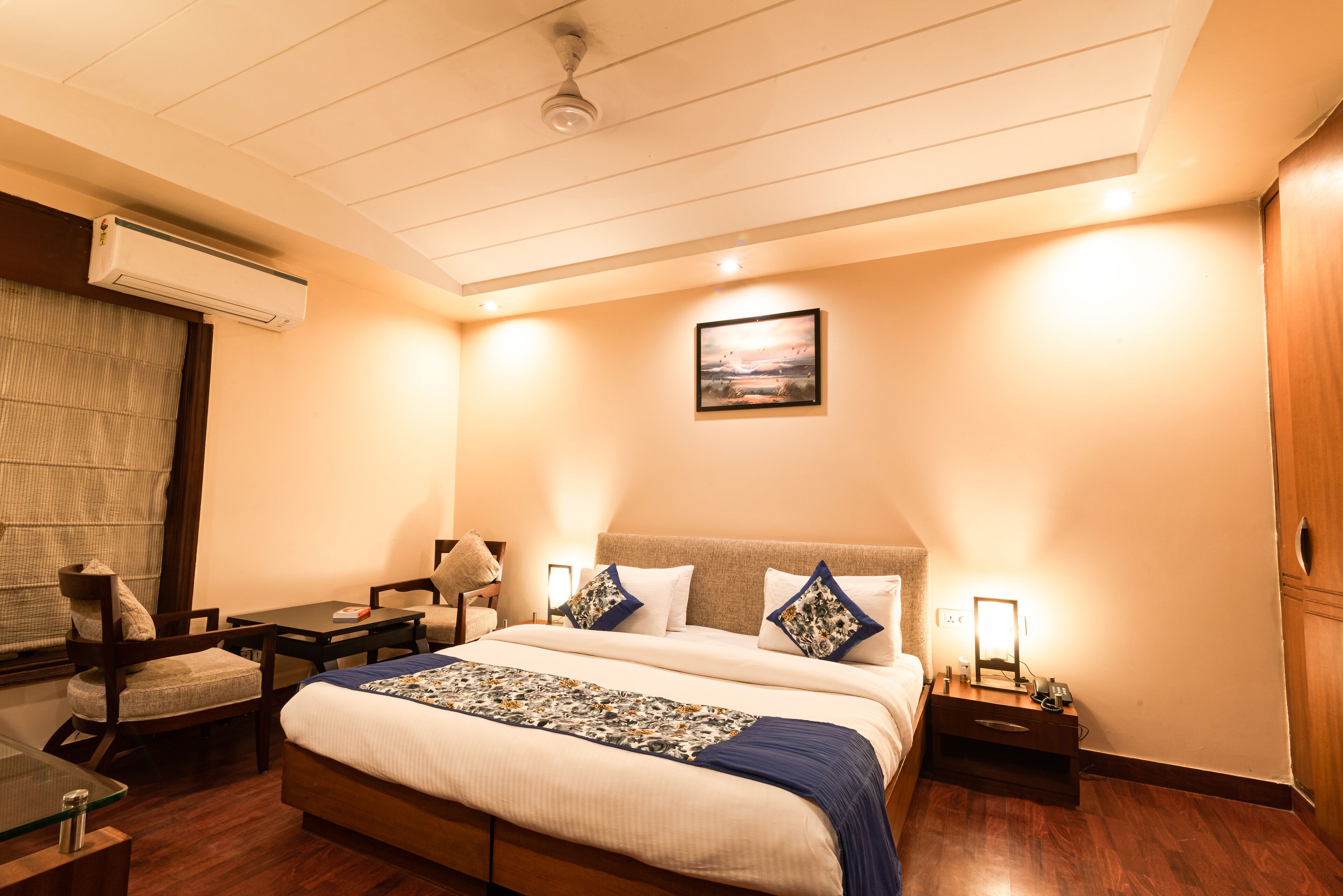 A hotel room with a bed, bedside tables, a desk, and a chair.