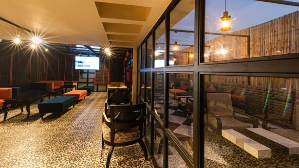 A modern interior with a checkered floor, seating areas, and large windows offering views of the outside. - Shubham Vilas - Hostel (New Delhi)
