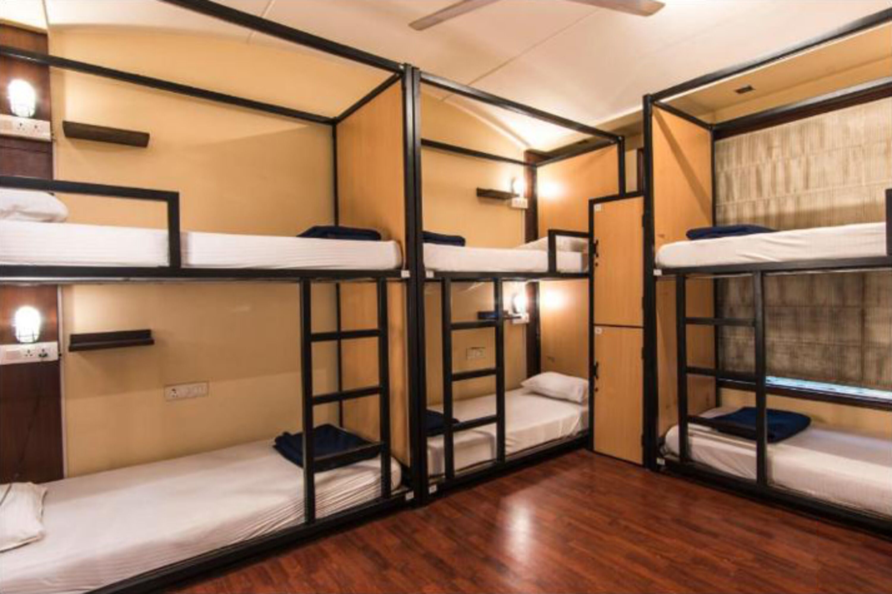 Quarto com beliches, piso de madeira e ventilador de teto.