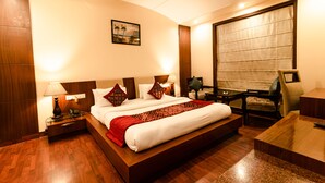 A hotel room with a large bed, bedside tables, a desk, and a chair. - Shubham Vilas - Hostel (New Delhi)