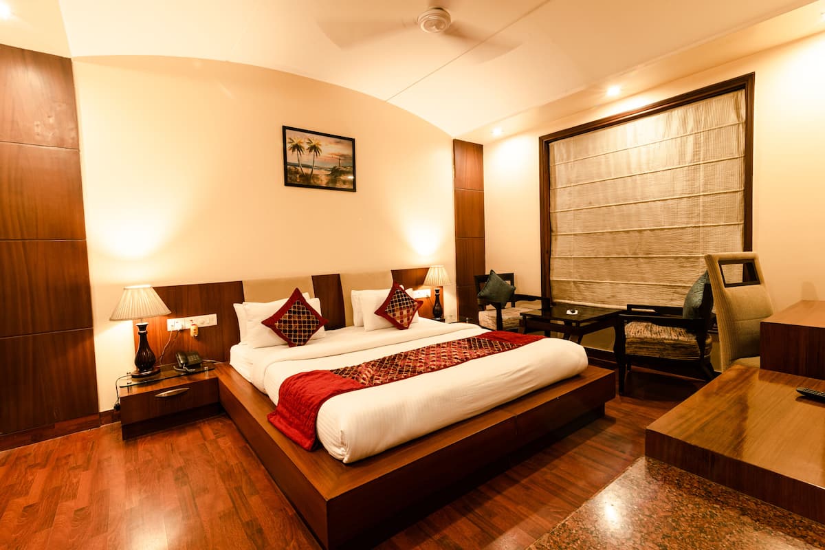 A hotel room with a large bed, bedside tables, a desk, and a chair.
