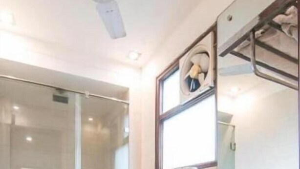A modern bathroom with a glass shower enclosure, a white sink with a marble countertop, and a large mirror. - Shubham Vilas - Hostel (New Delhi)