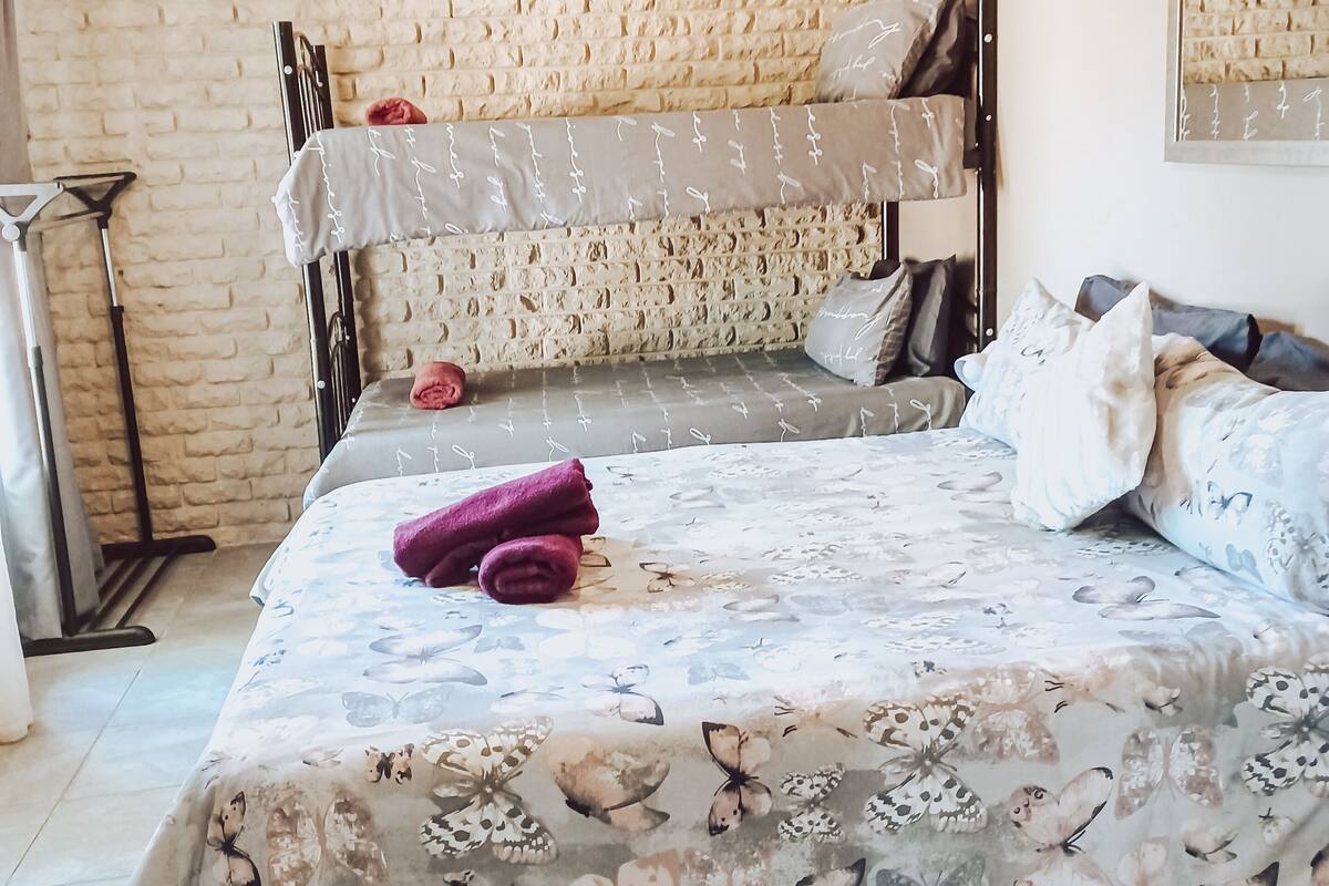 A bunk bed room with a floral bedspread, a mirror on the wall, and a brick wall.