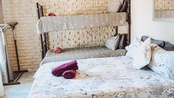 A bunk bed room with a floral bedspread, a mirror on the wall, and a brick wall.