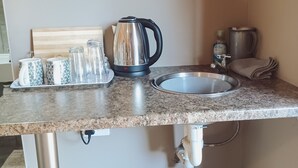 A kitchen with a granite countertop, a kettle, a sink, and a trash bin. - Ambiente Budget Accommodation (Upington)