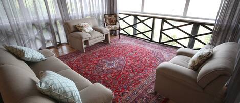 Una sala de estar con dos sofás, un tapete estampado y una silla.