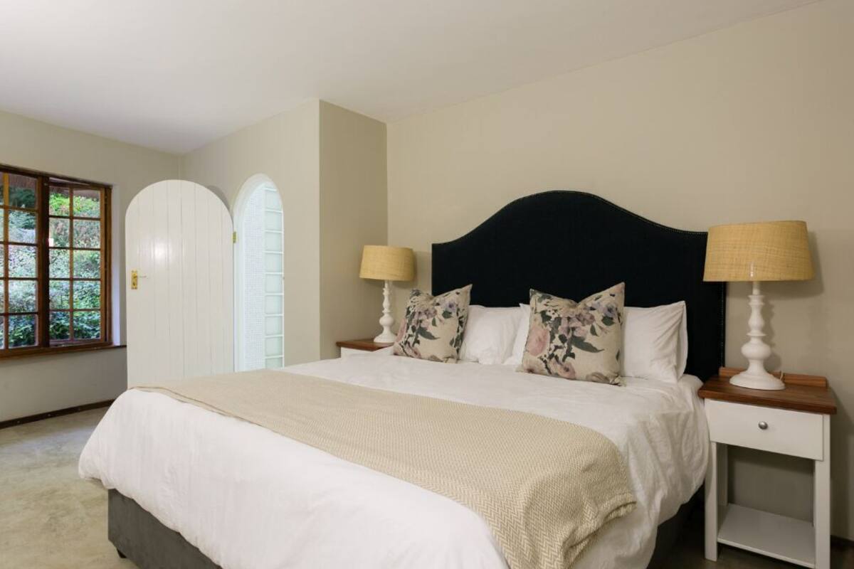 A bedroom with a bed, two bedside tables, a window, and a door.