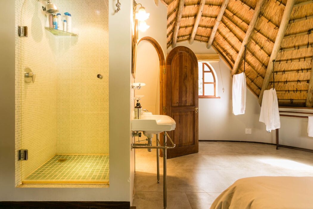 Un baño con ducha, lavamanos y puerta de madera.