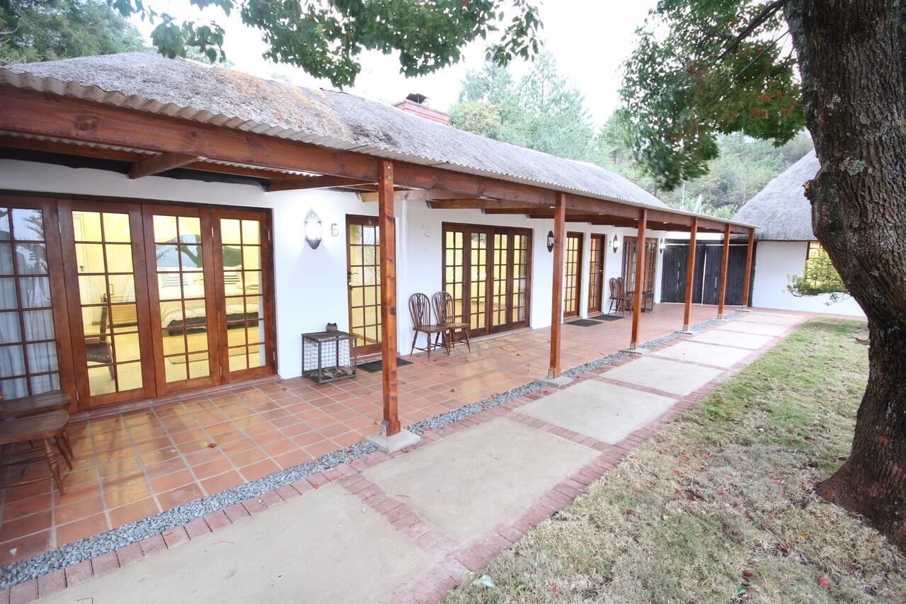A traditional house with a thatched roof, wooden beams, and a tiled patio area with outdoor seating.