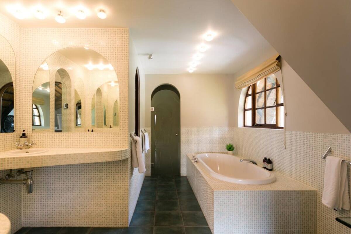 A bathroom with a large mirror, a bathtub, and a sink.