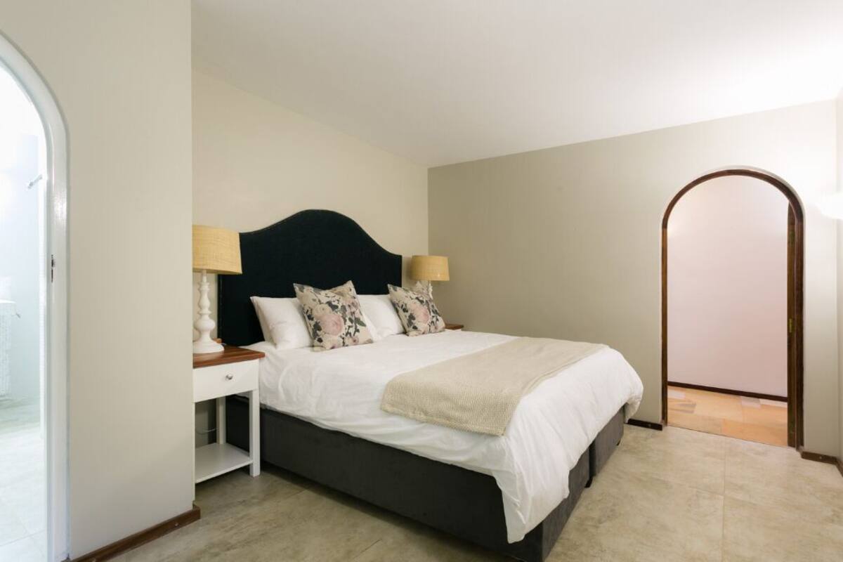 A bedroom with a bed, nightstands, and a mirror.