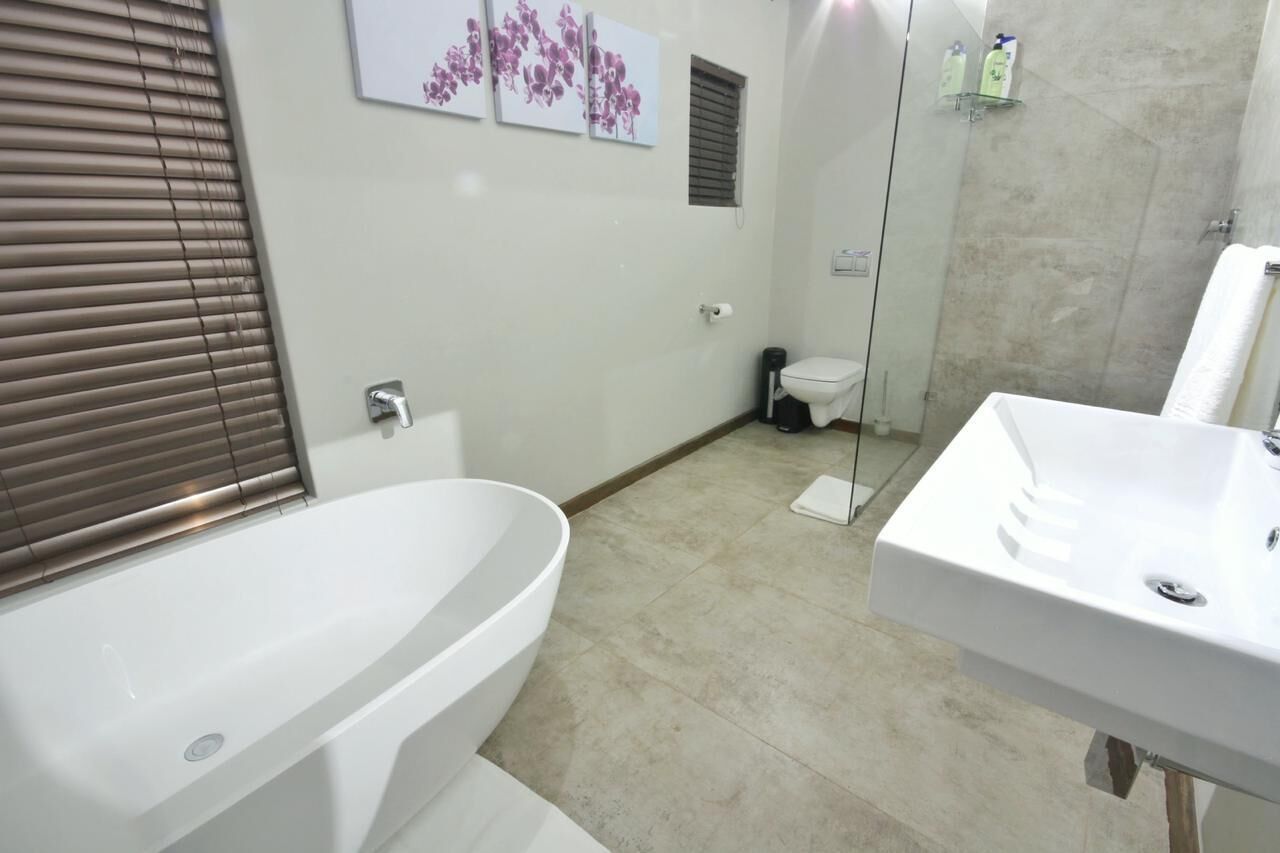 Un bagno moderno con una vasca freestanding, un lavandino ampio e una zona doccia con pareti in vetro.