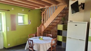 A kitchen with a wooden staircase, a dining table with chairs, and a refrigerator.
