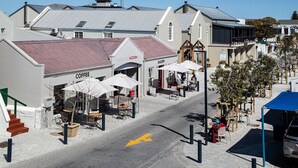 Une rue bordée de commerces, notamment une boulangerie et un café, ainsi qu’un trottoir réservé aux piétons.