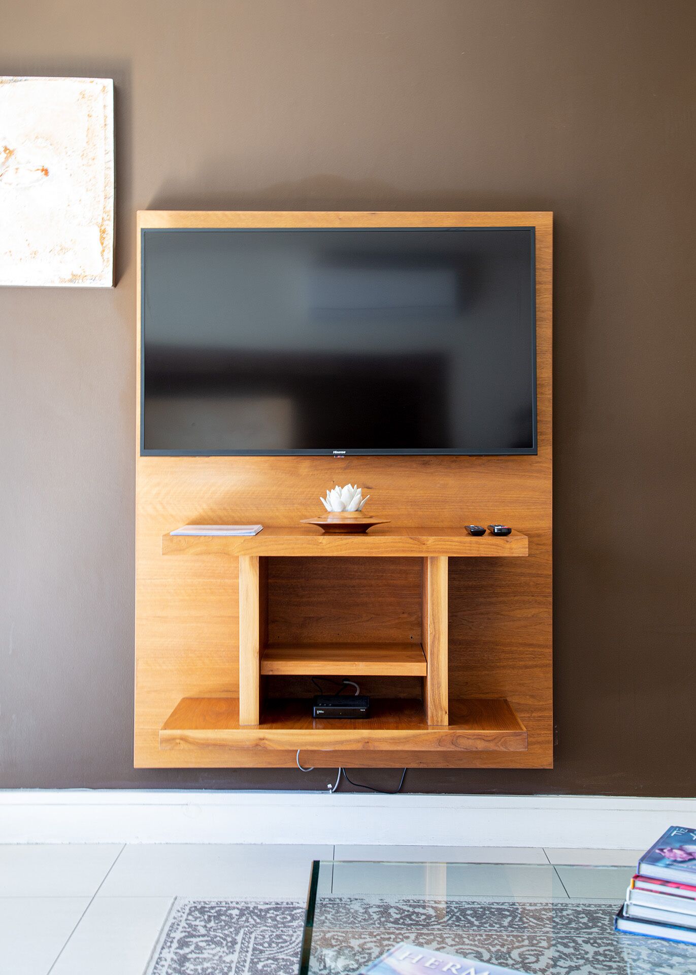 A flat-screen TV mounted on a wooden wall unit with a small shelf below.