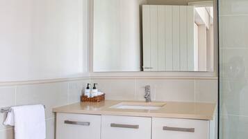 A modern bathroom with a large mirror, a sink, and wooden cabinetry.