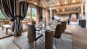 A spacious dining area with a glass table and chairs, wooden beams on the ceiling, and large windows with curtains. - Luxury chalet with pool and spa in Courchevel (Courchevel)
