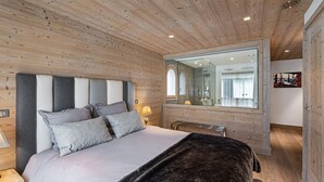 A bedroom with a large bed, a wooden ceiling, and a mirror. - Luxury chalet with pool and spa in Courchevel (Courchevel)