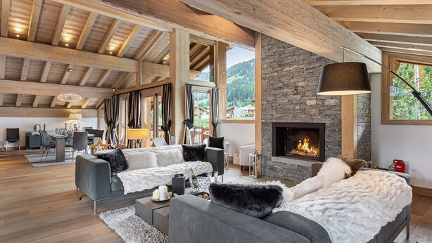 A spacious living room with a stone fireplace, wooden beams, and a large window overlooking a mountainous landscape. - Luxury chalet with pool and spa in Courchevel (Courchevel)