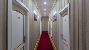 Un couloir avec les portes numérotées 501 et 506, une moquette rouge et des lampes fixées au mur.